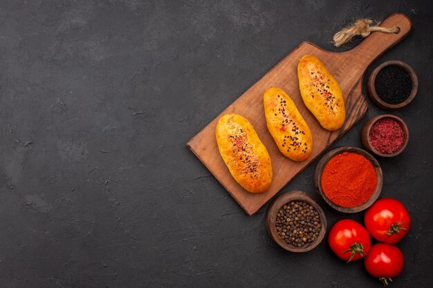 Vista superior deliciosas empanadas al horno recién salido del horno con condimentos en el fondo gris horno de pastel de carne pastelería pastel hornear