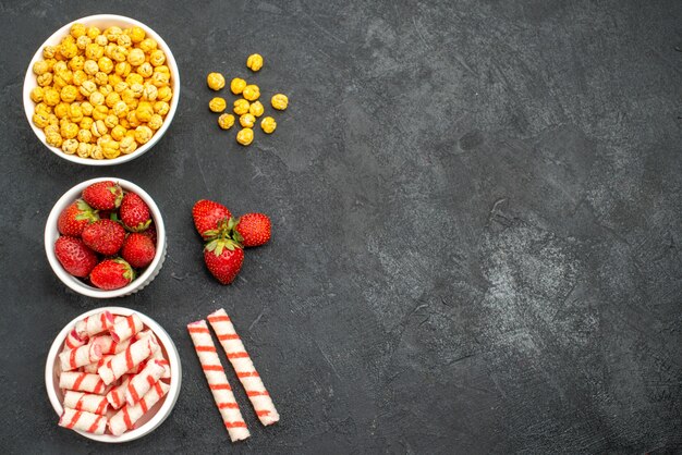 Vista superior de deliciosas fresas con dulces sobre un fondo negro con espacio libre