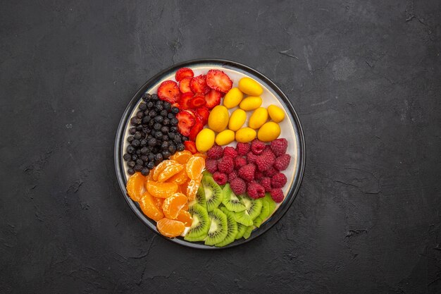 Vista superior deliciosas frutas en rodajas dentro de la placa en frutas tropicales oscuras dieta madura exótica