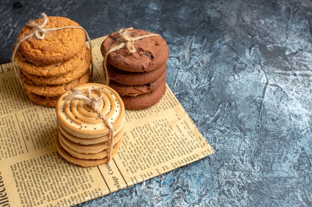 Vista superior de deliciosas galletas apiladas en un periódico viejo sobre fondo oscuro