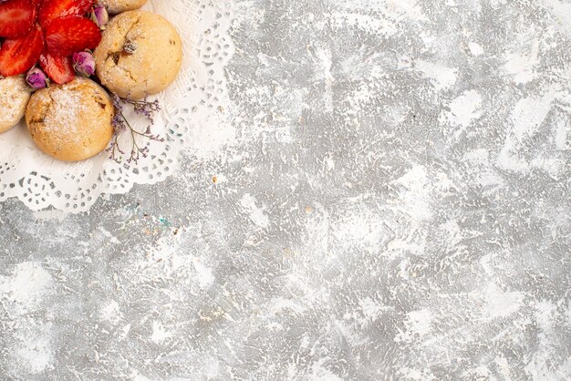 Vista superior de deliciosas galletas de arena con fresas frescas en la superficie blanca