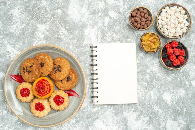 Vista superior deliciosas galletas de arena con galletas dulces y caramelos sobre fondo blanco pastel de galletas té dulce té