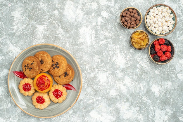 Vista superior deliciosas galletas de arena con galletas dulces y caramelos sobre fondo blanco pastel de galletas té dulce té
