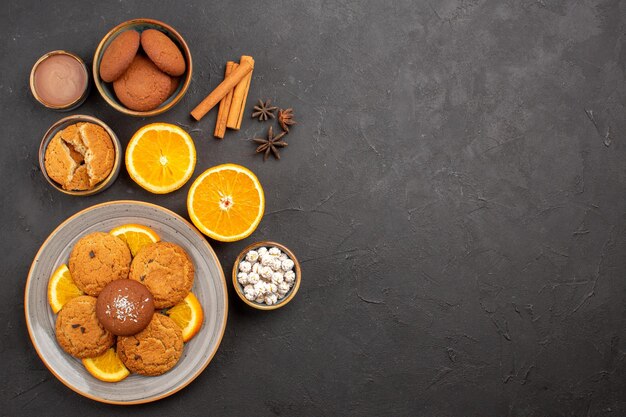 Vista superior deliciosas galletas de arena con naranjas frescas en rodajas sobre fondo oscuro galleta de frutas galletas dulces azúcar color cítrico