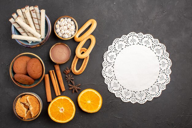 Vista superior deliciosas galletas de arena con naranjas frescas en rodajas sobre fondo oscuro galletas azúcar fruta dulce galleta cítrica