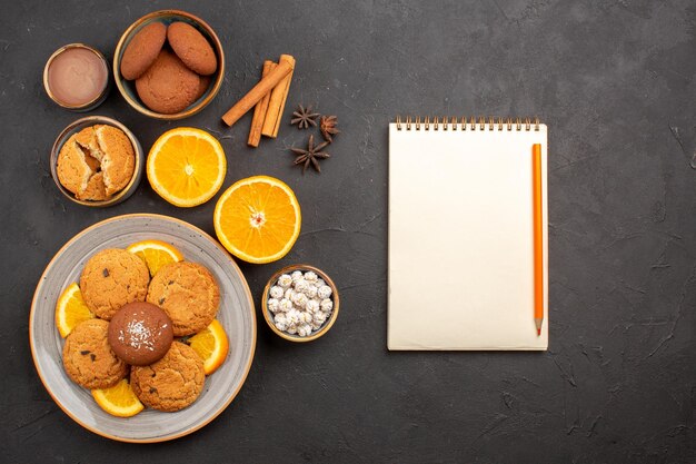 Vista superior deliciosas galletas de arena con naranjas frescas en rodajas sobre fondo oscuro galletas de frutas galletas dulces azúcar color cítrico