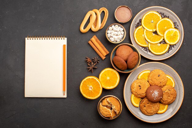 Vista superior deliciosas galletas de arena con naranjas frescas sobre fondo oscuro galleta de frutas cítricos de galletas dulces