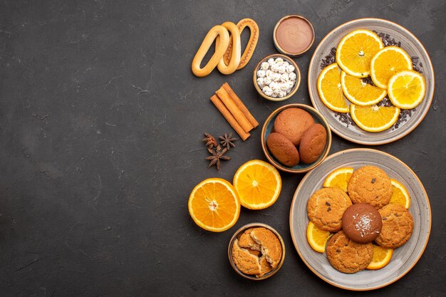 Vista superior deliciosas galletas de arena con naranjas frescas sobre fondo oscuro galleta de frutas cítricos de galletas dulces