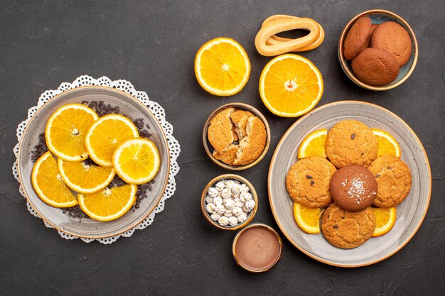 Vista superior deliciosas galletas de arena con naranjas en rodajas sobre fondo oscuro galletas cítricas de frutas pastel dulce galleta