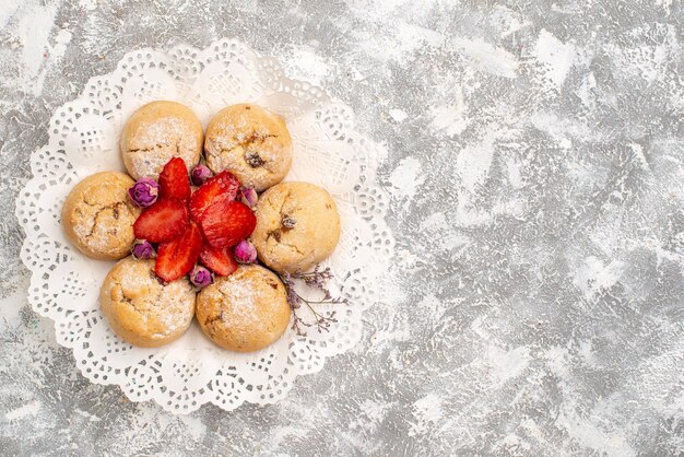 Vista superior de deliciosas galletas de azúcar con fresas en superficie blanca