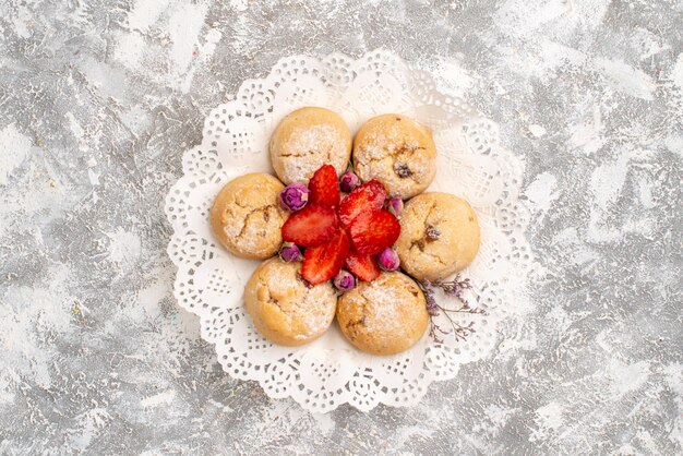 Vista superior de deliciosas galletas de azúcar con fresas en superficie blanca