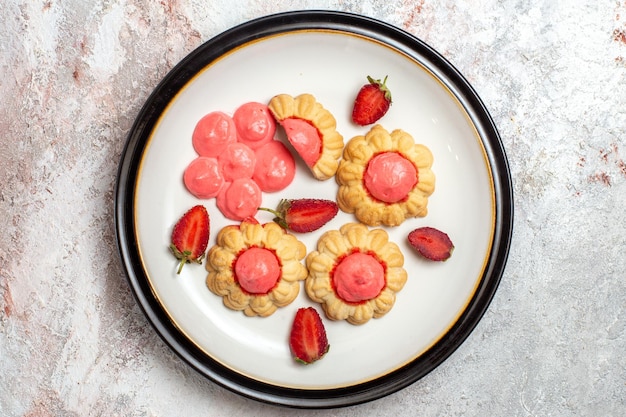 Vista superior de deliciosas galletas de azúcar con gelatina de fresa sobre superficie blanca