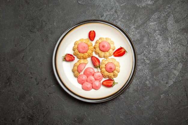 Vista superior de deliciosas galletas de azúcar con gelatina de fresa en la superficie gris