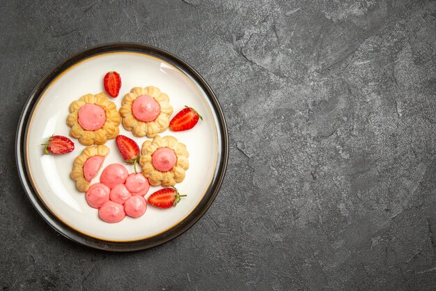 Vista superior de deliciosas galletas de azúcar con gelatina de fresa en la superficie gris