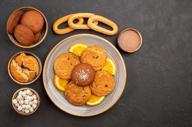 Vista superior deliciosas galletas de azúcar con naranjas frescas en rodajas en el escritorio oscuro galleta galleta pastel de azúcar postre dulce