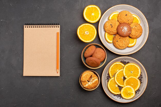 Vista superior deliciosas galletas de azúcar con naranjas frescas en rodajas sobre el fondo oscuro galleta de azúcar galleta dulce pastel de frutas