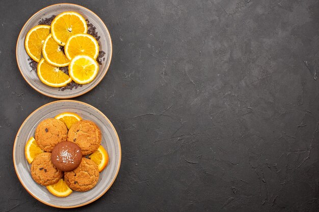 Vista superior deliciosas galletas de azúcar con naranjas frescas en rodajas sobre fondo oscuro galleta de azúcar galletas dulces fruta