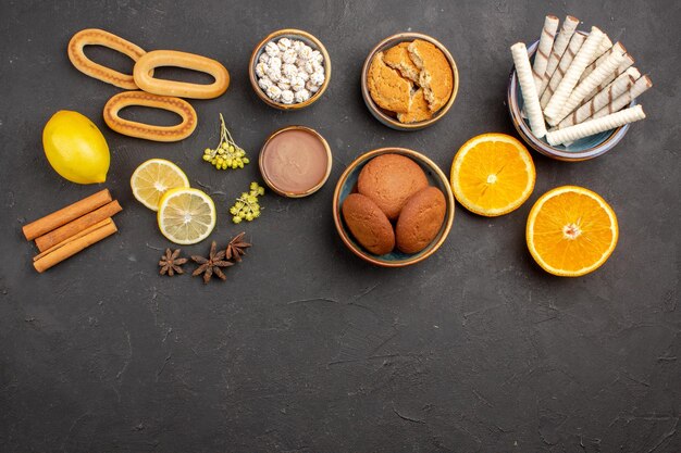 Vista superior deliciosas galletas de azúcar con naranjas en rodajas sobre el fondo oscuro, azúcar, té, galleta, galleta, fruta dulce