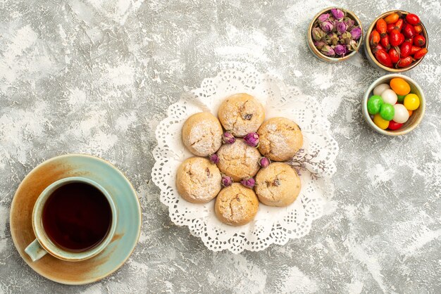 Vista superior deliciosas galletas de azúcar con una taza de té en la superficie blanca galleta de azúcar galleta pastel de té dulce