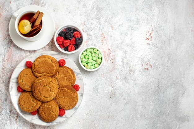 Vista superior de deliciosas galletas de azúcar con una taza de té en la superficie blanca