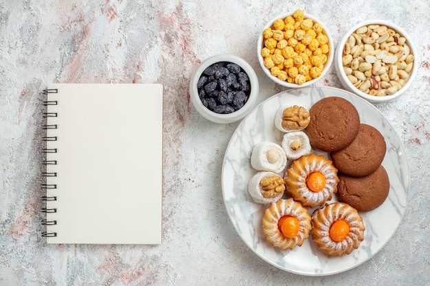 Vista superior deliciosas galletas con caramelos y nueces en el escritorio blanco pastel dulce galleta galleta nuez