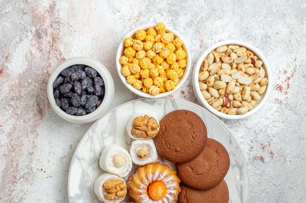 Vista superior deliciosas galletas con caramelos y nueces sobre fondo blanco galleta pastel dulce galleta tuerca