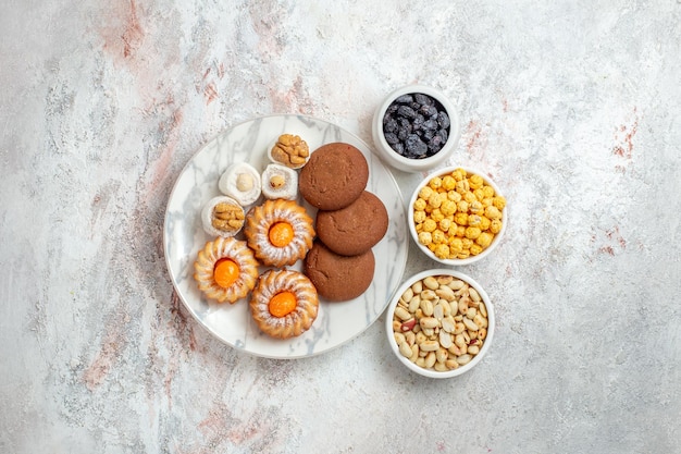 Vista superior deliciosas galletas con caramelos y nueces sobre fondo blanco pastel dulce galleta galleta nuez