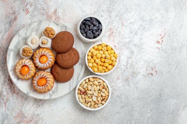 Vista superior deliciosas galletas con caramelos y nueces sobre fondo blanco pastel galleta galleta dulce azúcar té