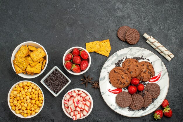 Vista superior deliciosas galletas choco con diferentes bocadillos en el escritorio oscuro té dulce de galletas