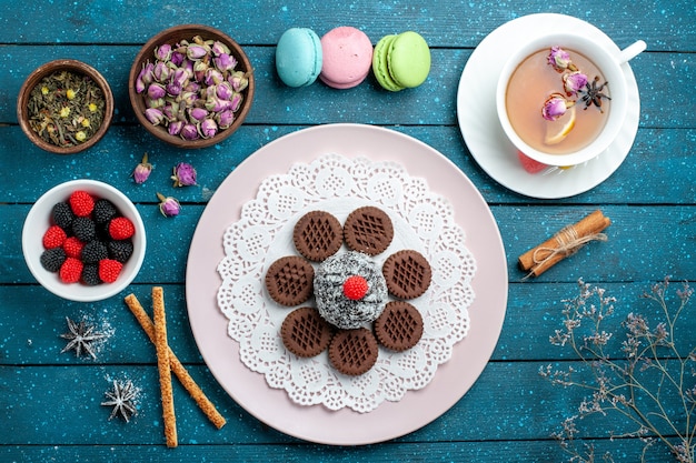 Vista superior deliciosas galletas de chocolate con confituras y té en el escritorio rústico azul pastel de té de cacao galleta de galletas dulces