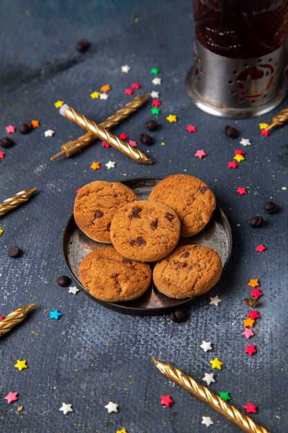 Vista superior deliciosas galletas de chocolate dentro de la placa con pequeños letreros de estrellas de colores y velas en el escritorio oscuro galleta galleta azúcar té dulce