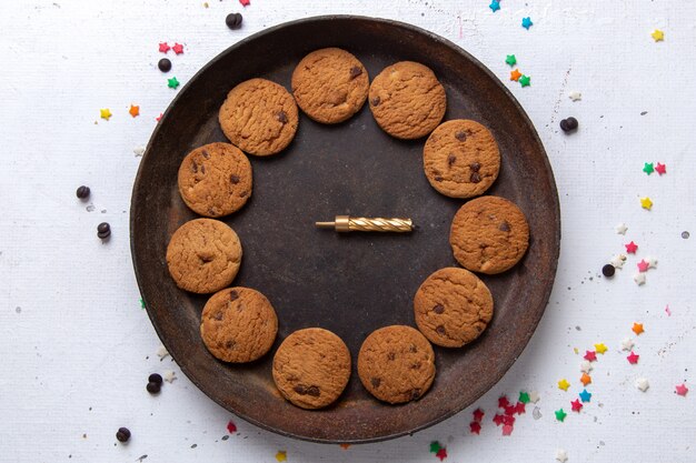 Vista superior deliciosas galletas de chocolate dentro de la placa redonda marrón sobre el fondo blanco galleta galleta azúcar dulce