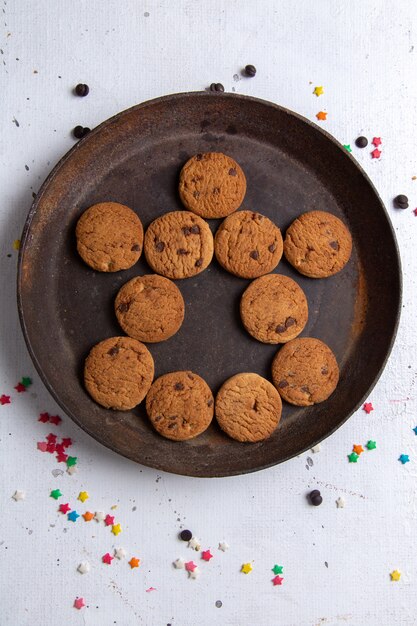 Vista superior deliciosas galletas de chocolate dentro de la placa redonda oscura sobre el fondo blanco galleta galleta azúcar té dulce