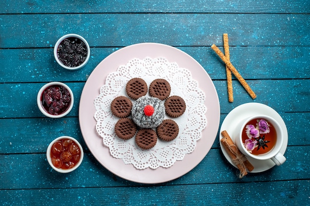 Vista superior de deliciosas galletas de chocolate con mermelada y taza de té en el escritorio rústico azul galleta de té galleta dulce pastel de azúcar