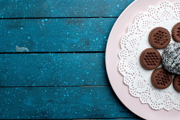 Vista superior deliciosas galletas de chocolate con pastel de chocolate en el escritorio rústico azul pastel de té de cacao galleta dulce galleta
