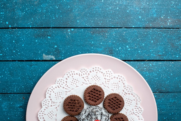 Vista superior deliciosas galletas de chocolate con pastel de chocolate sobre fondo rústico azul pastel de té de cacao galleta de galleta dulce