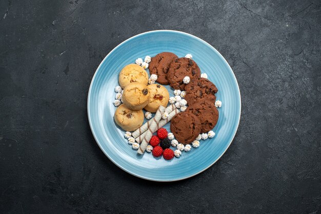 Vista superior deliciosas galletas de chocolate y sencillas con caramelos en la superficie gris oscuro pastel de galletas de azúcar galleta dulce