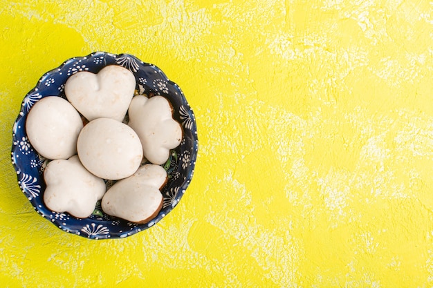 Foto gratuita vista superior de deliciosas galletas dentro de la placa azul sobre la superficie amarilla