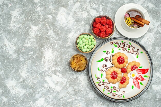 Vista superior deliciosas galletas dulces con caramelos y taza de té en blanco
