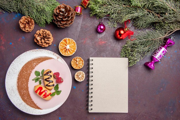 Vista superior deliciosas galletas dulces con juguetes navideños y árbol sobre fondo oscuro galleta galleta dulce pastel de color azúcar