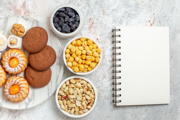 Vista superior deliciosas galletas con dulces y nueces sobre fondo blanco pastel dulce galleta galleta azúcar té