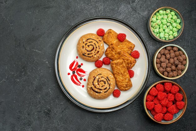 Vista superior deliciosas galletas dulces con otros caramelos dulces sobre fondo gris galleta dulce azúcar pastel galleta té