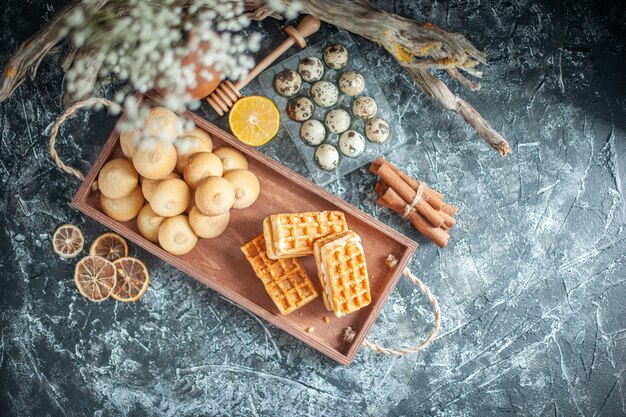 Vista superior deliciosas galletas dulces con pequeños pasteles sobre fondo gris claro pastel dulce de azúcar de color pastel de nuez de galleta