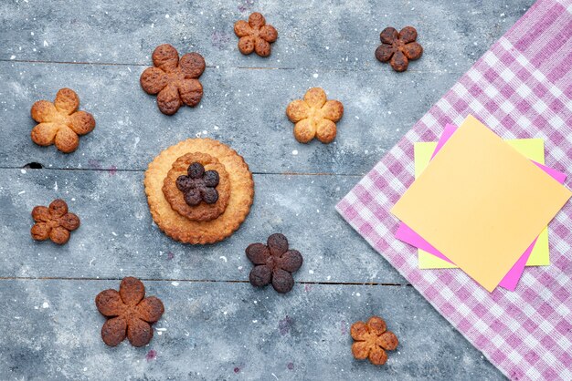 Vista superior de deliciosas galletas dulces repartidas por todo el escritorio gris de madera, galleta de azúcar galleta dulce