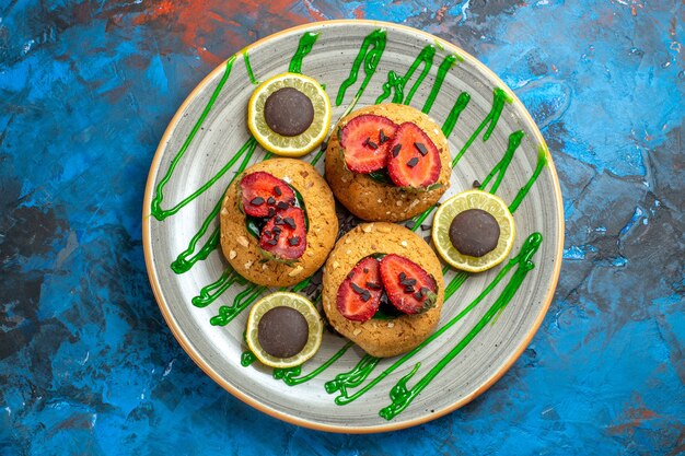 Vista superior deliciosas galletas con frutas dentro de la placa en la fruta dulce de la galleta azul