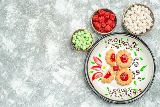 Vista superior deliciosas galletas con gelatina roja y caramelos sobre fondo blanco galleta de pastel de galleta dulce