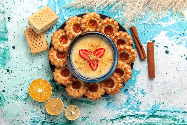 Vista superior deliciosas galletas con mermelada y postre de fresa en el escritorio azul