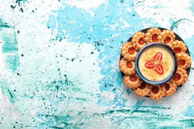 Vista superior deliciosas galletas con mermelada y postre de fresa sobre fondo azul claro postre de pastel de galleta dulce de azúcar