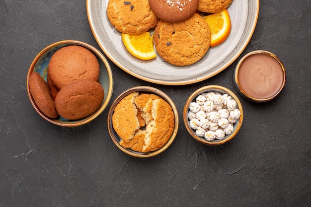 Vista superior deliciosas galletas con naranjas frescas en rodajas sobre fondo oscuro galleta galleta fruta dulce pastel de cítricos