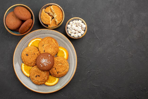 Vista superior deliciosas galletas con naranjas frescas en rodajas sobre fondo oscuro pastel de galletas de frutas cítricos galletas dulces